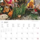 Juli 2027. Bunt gekleidete Teddybären genießen im Gras einen Sommertag. Ein Vogel sitzt auf einem Sonnenschirm.