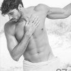 Juli, Juillet, Luglio, July. Ein muskulöser Mann mit Hand auf Brust, in ein Handtuch gehüllt. Unten ist eine Kalenderansicht.