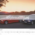"Vorjahresabbildung" steht auf einem transparenten Balken. Zwei BMWs, ein roter und ein blauer, in Landschaft bei Sonnenuntergang.