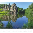 Kalender mit Juli 2027-Daten. Landschaft mit großen Felsen, See und Bäumen, klare Spiegelung im Wasser.