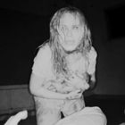 Ein Raum in Dunkelheit; im Vordergrund kniet eine Frau mit nassen Haaren und erschrockenem Gesichtsausdruck.