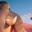 Ein großer, freundlicher Elefant schaut auf eine kleine Maus, die auf seinem erhobenen Rüssel steht.