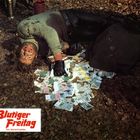 "Blutiger Freitag" und "Ein Gloria-Farbfilm" steht auf einem Schild. Ein Mann liegt auf Laub, umgeben von Geldscheinen.