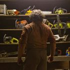 Ein Mann steht vor Regalen mit Kettensägen und Werkzeugen. Oberhalb sind diverse Kettensägen in verschiedenen Farben.