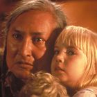 Ein älterer Mann hält ein blondes Kind nah bei sich, beide wirken ernst und nachdenklich.