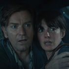 Zwei Personen sitzen verängstigt in einem Auto, sich fest umarmend, mit ängstlichen Gesichtsausdrücken.