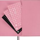 Mehrere Bögen mit Symbolen, Buchstaben und Zahlen in Weiß auf rosa und schwarzem Hintergrund, in einem rosa Notizbuch.