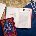 Ein aufgeschlagenes Buch zeigt den Text über "Jihad, noun" und einen Absatz unter "SYRIA". Daneben liegt ein Buch mit dem Titel "THE OCEAN WOULD PAINT ME BLUE".
