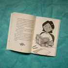 Text auf Seite: Diskussion über Stegosaurus-Projekt. Illustration: Person liest Buch am Tisch mit Stiften und Papier.