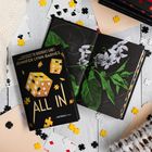 Ein Buchcover zeigt den Titel "ALL IN" von Jennifer Lynn Barnes mit Würfeln und Puzzleteilen. Daneben ein aufgeschlagenes Buch mit Blumen. Karten und Puzzleteile liegen verstreut.