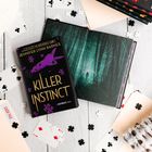 Text: "KILLER INSTINCT", "JENNIFER LYNN BARNES", "CASE FILE". 

Ein Buch mit einem stilisierten Rätselmotiv auf einem Tisch mit Spielkarten.