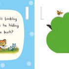 Text: "Little Cub is looking for Daddy. Is he hiding behind the bush?" Illustration: Ein kleiner Löwe und ein grüner Busch.
