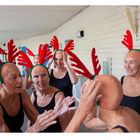 Texte: "Members of the Sun City Aqua Suns synchronized swimming team..." 

Frauen mit roten Rentiergeweihen bereiten sich auf eine Schwimm-Performance vor.