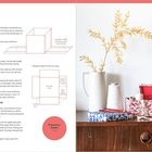 Texte beschreiben Boxen und Papierschneiden. Rechts Vase mit Zweigen, Garnspulen, bunte Boxen auf Holzkommode.