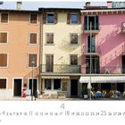Porto. Häuserfassaden in warmen Farben, Balkone und eine Café-Terrasse mit Tischen und Stühlen.