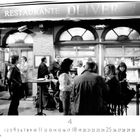 Beschriftung: "RESTAURANTE OLIVER CAFÉ BAR". Menschen versammeln sich vor dem Restaurant und unterhalten sich.