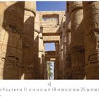 Amun Tempel Karnak. Kalenderseite für April. Massive dekorierte Säulen im Vordergrund, dahinter blauer Himmel und Palmen.