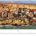 "Popeye Village". Eine Küstenstadt mit bunten Holzhäusern vor einer steinigen Klippe am türkisfarbenen Meer.