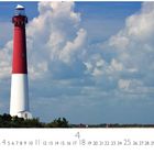 "Barnegat Lighthouse N.Y." Ein rot-weißes Leuchtturm vor blauem Himmel mit Wolken, umgeben von Vegetation.