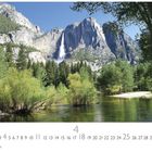 „Yosemite“ steht unter einem Wasserfall, der von hohen Bergen umgeben ist; im Vordergrund ein Fluss in grüner Landschaft.