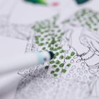 Eine Nahaufnahme einer Illustration: Eine Person wird teilweise mit grünen Punkten ausgemalt. Ein Stift ist zu sehen.