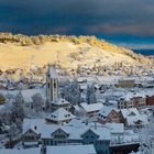 Text beschreibt Thal, ein Dorf mit Kirche aus dem 700. Jahrhundert, umgeben von Hügeln, bedeckt mit Schnee und Bäumen.