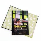 "Miezen im Mezzanin: Ein Wiener Stadtporträt in 23 Katzen" - Buch mit Katze und dekorativem Katzenmuster im Hintergrund.