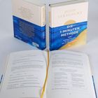 Der Text auf dem vorderen Buch: "John Strelecky, Die 1-Minuten Methode, Der einfache Weg zu dem Leben, das du dir wünschst." Aufgeschlagenes Buch zeigt Übungen und Tipps.