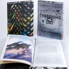 Der Titel lautet „THRESHING DAY: FLAMMENGEKÜSST“. Es sind drei Bücher zu sehen, eines zeigt ein drachenähnliches Wesen.