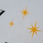 Großes "Z" in schwarzer Schrift, gelbe Sterne im Hintergrund auf grauem Untergrund.