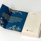 Zitat über emotionale Tiefe und Wendungen, von Santa Montefiore. Goldene Blumen auf blauem Hintergrund.