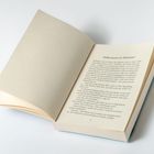 Aufgeschlagenes Buch, Seiten mit gedrucktem Text. Überschrift: "Willkommen im Wahnsinn!" Links leere Seite.