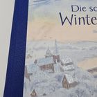 „Die schönsten Winter“, Illustration: Eine verschneite Dorflandschaft mit Kirche und beleuchteten Fenstern, glitzernde Details.