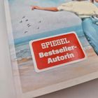 "SPIEGEL Bestseller-Autorin" auf rotem Sticker. Illustration zeigt Frau am Strand, die auf das Meer zeigt, Möwen fliegen.