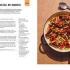 "Teriyaki-Hähnchenflügel mit Kokosreis". Eine Pfanne mit glasierten Hähnchenflügeln auf Reis, garniert mit Frühlingszwiebeln.