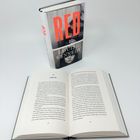 Ein geschlossenes Buch "RED" von Louise Kennedy, steht hinter einem aufgeschlagenen Buch.