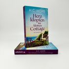 „H.C. HOPE - Herzklopfen im kleinen Cottage“. Ein Buchcover zeigt ein Cottage an der Küste.