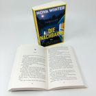 Buchcover: "NOVA WINTER, THRILLER, DIE NACHBARIN, LASS SIE NICHT IN DEIN HAUS." Ein geöffnetes Buch liegt daneben.