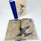 Text: "Das Buch der Vögel". Ein geschlossenes und ein offenes Buch mit Vogelbildern. Cover zeigt zwei Vögel auf Ästen.