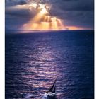 04, Zahlenreihe 01 bis 30. Ein Segelboot auf offenem Meer, Sonnenstrahlen durchbrechen dramatische Wolken.