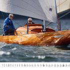 Zahl 4 unten links, darunter kleiner Kalender. Zwei Personen segeln auf einem eleganten Holzsegelboot auf dem Wasser.