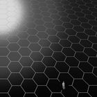 Keine erkennbaren Texte. Eine Person steht auf einem großen Feld aus schwarzen, sechseckigen Kacheln mit einem Lichteffekt oben links.