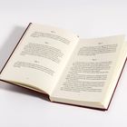Ein geöffnetes Buch mit Texten zu Kapiteln 2 bis 6 auf cremigen Seiten, rotem Einband.