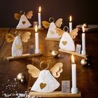 „Frohe Festtage euch allen!“ Mehrere Engel aus Stoff mit goldenen Flügeln, Kerzen, goldene Kugeln auf Holztisch.