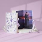 Buch mit dem Titel "Stay Here" von Anna Savas. Daneben eine Illustration eines Paares vor einem Sternenhimmel.