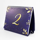 Eine große goldene Zahl "2" auf einem dunkelblauen Kalender mit goldenen Sternen und Blättermotiven.