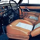 Kein Text erkennbar. Lenkrad, Tachometer und braune Ledersitze in einem klassischen Auto-Innenraum.