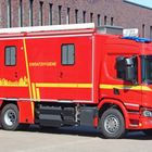 Rotes Einsatzfahrzeug mit den Worten "FEUERWEHR KREFELD" und "EINSATZHYGIENE". 442 und Stadt-Silhouette in Gelb.