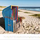 Kalender: April, Strandkörbe am Sandstrand mit Meer im Hintergrund, blauer Himmel, leicht bewölkt.