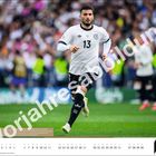 Text "Voriahresabbildung" über einem Fußballspieler in einem weißen Trikot mit der Nummer 13 auf einem Spielfeld.